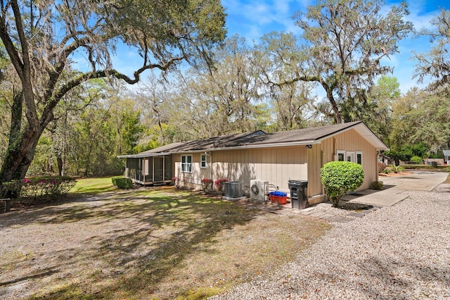 exterior space with cooling unit, a lawn, and a sunroom