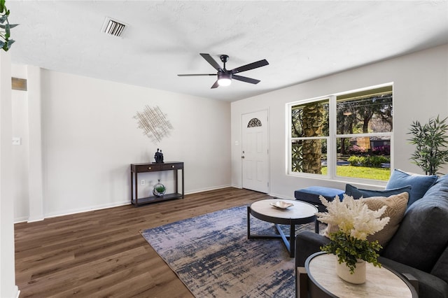 living room featuring visible vents, ceiling fan, baseboards, and wood finished floors