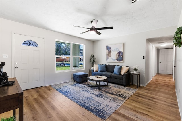 living room with a ceiling fan, wood finished floors, and a textured ceiling