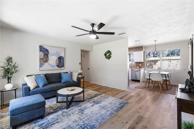 living area featuring light wood-style flooring, baseboards, visible vents, and ceiling fan