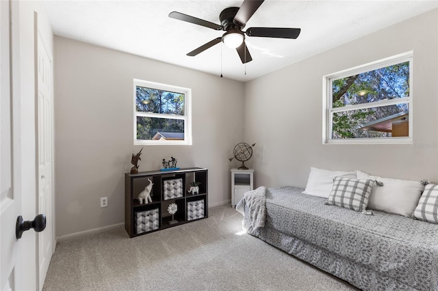 carpeted bedroom with ceiling fan and baseboards