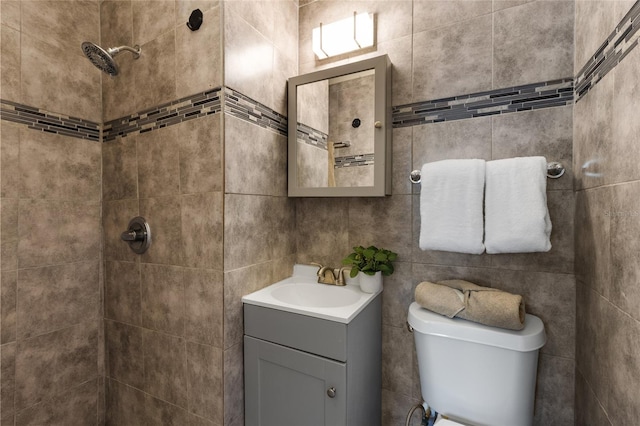 bathroom featuring toilet, tiled shower, and vanity