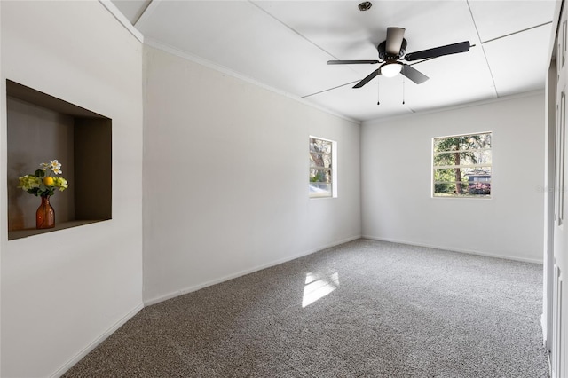 carpeted spare room with ceiling fan, baseboards, and ornamental molding