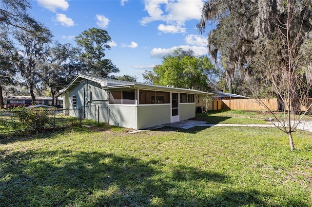 rear view of property with a fenced backyard, a yard, and a sunroom