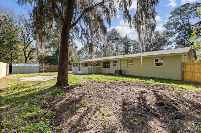 rear view of property with central AC unit and fence