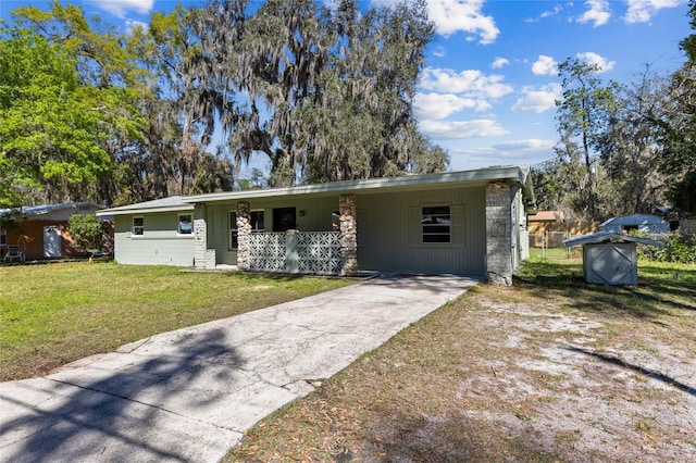 view of front of house featuring a front yard, concrete driveway, covered porch, and stone siding