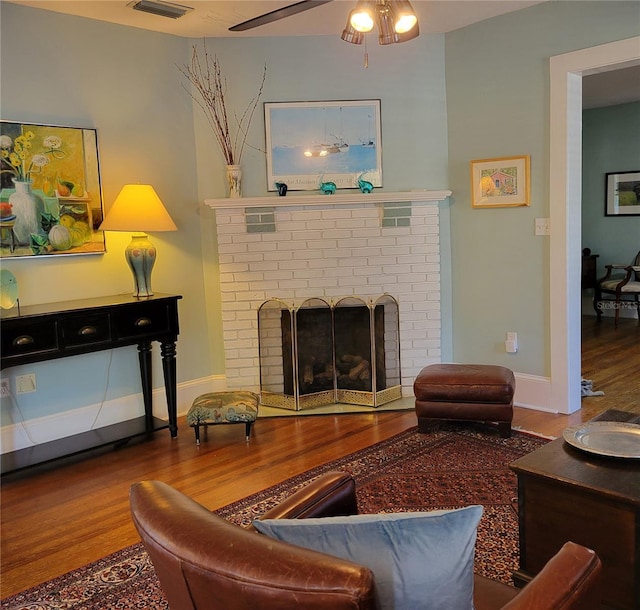 living room with baseboards, visible vents, wood finished floors, and a ceiling fan