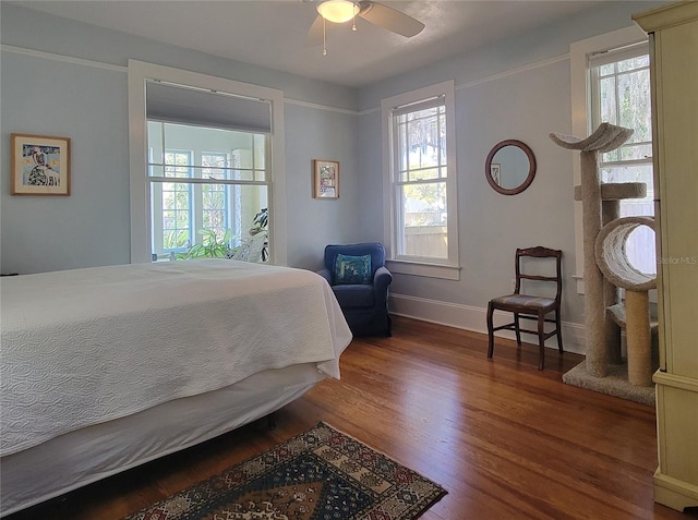 bedroom with baseboards, wood finished floors, and multiple windows