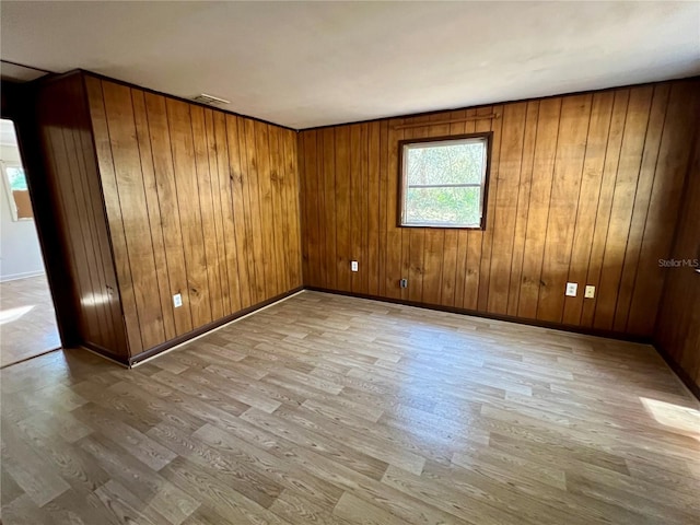 spare room featuring baseboards, wooden walls, and wood finished floors