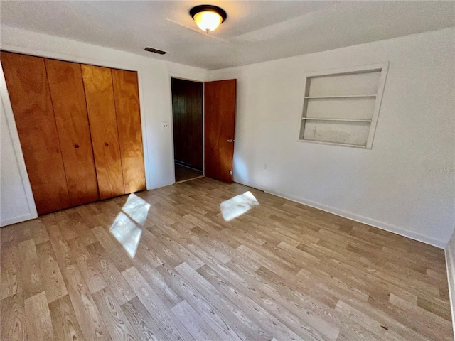 unfurnished bedroom featuring a closet, light wood-style floors, and visible vents