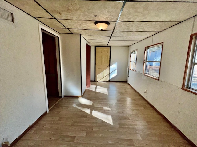 empty room featuring visible vents, wood finished floors, baseboards, and a wealth of natural light