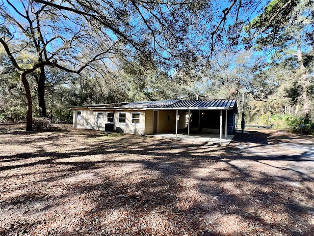 rear view of property with a carport, driveway, and metal roof