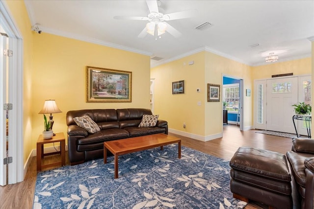 living area featuring visible vents, crown molding, baseboards, ceiling fan, and wood finished floors