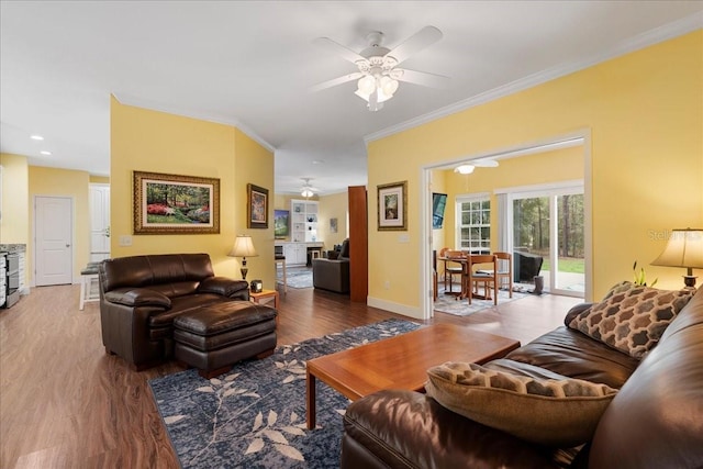 living room with ornamental molding, wood finished floors, baseboards, and ceiling fan