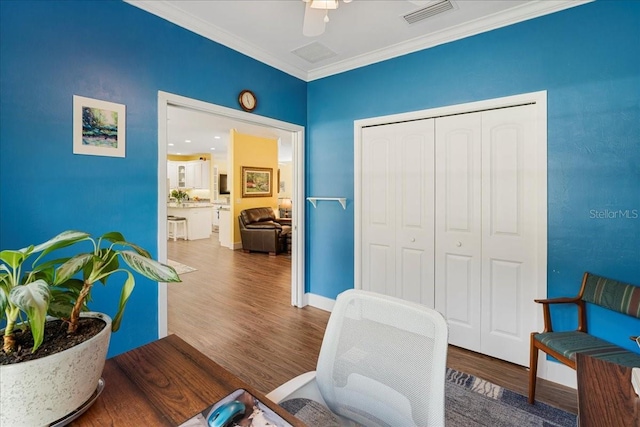 sitting room featuring visible vents, baseboards, wood finished floors, and ornamental molding