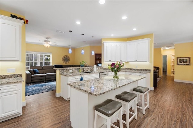 kitchen featuring ceiling fan, a kitchen breakfast bar, a peninsula, white cabinets, and a sink