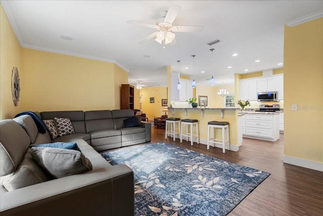 living area with visible vents, baseboards, ornamental molding, wood finished floors, and a ceiling fan