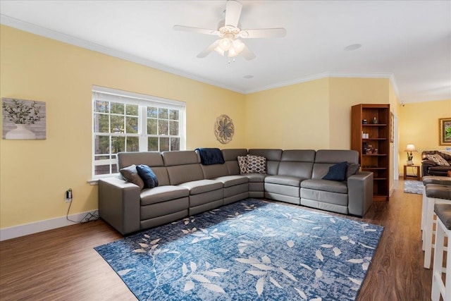 living area featuring a ceiling fan, wood finished floors, baseboards, and ornamental molding