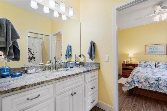 ensuite bathroom with ensuite bathroom, wood finished floors, baseboards, ceiling fan, and vanity