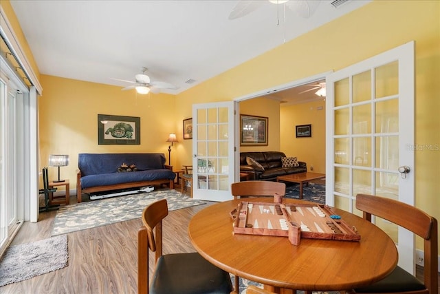 dining space with visible vents, ceiling fan, vaulted ceiling, french doors, and wood finished floors