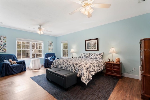 bedroom with a ceiling fan, crown molding, wood finished floors, and baseboards