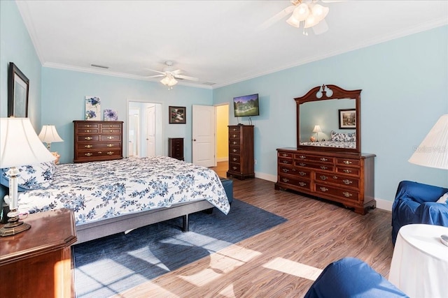 bedroom with visible vents, ornamental molding, wood finished floors, baseboards, and ceiling fan