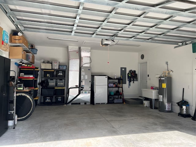 garage featuring electric panel, a sink, electric water heater, a garage door opener, and freestanding refrigerator