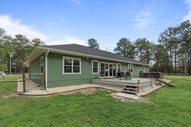 rear view of property featuring a yard, a hot tub, and a wooden deck