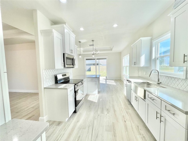 kitchen featuring a sink, a raised ceiling, appliances with stainless steel finishes, and light countertops