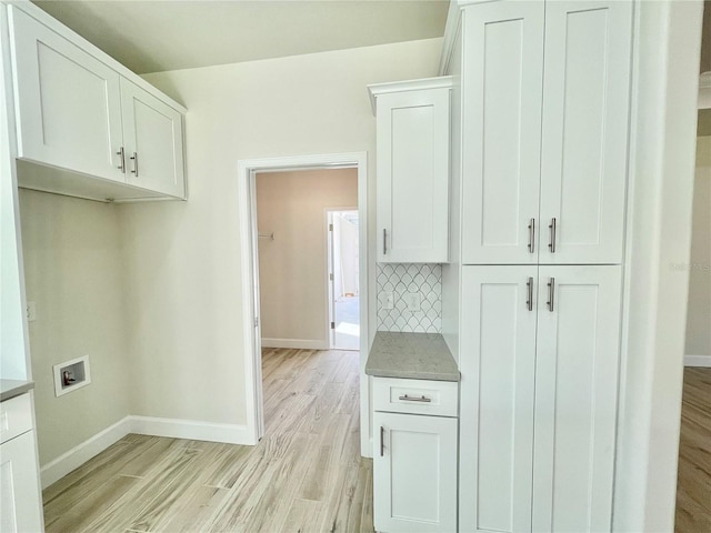 laundry room with hookup for a washing machine, cabinet space, light wood-style floors, and baseboards