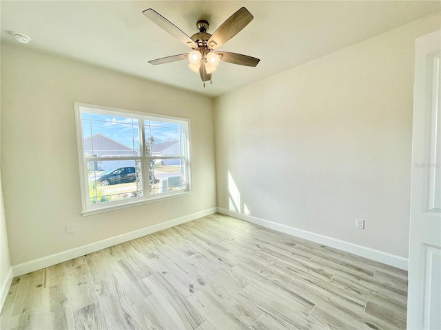 empty room featuring light wood finished floors, a ceiling fan, and baseboards