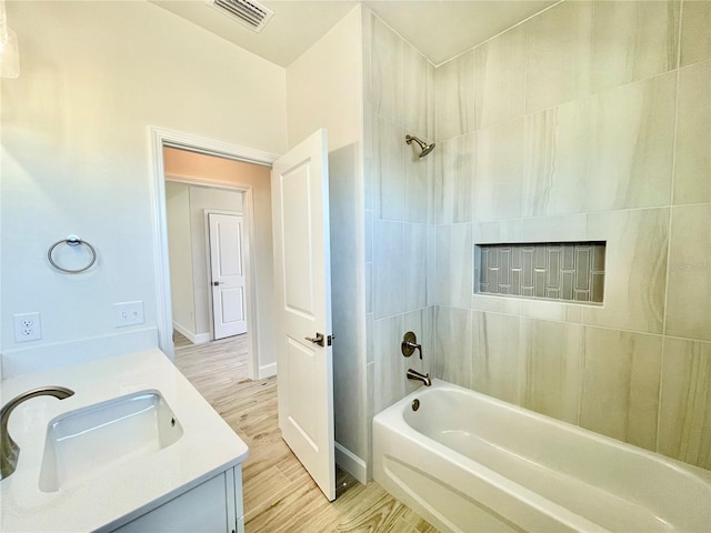 bathroom with vanity, wood finished floors, visible vents, baseboards, and shower / bathing tub combination