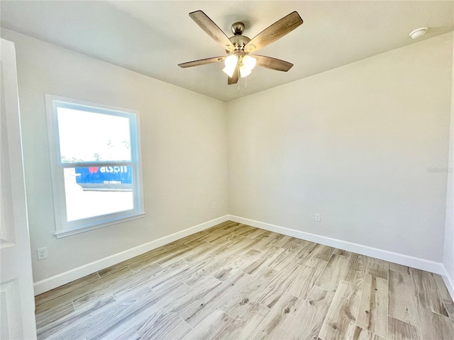 spare room featuring light wood-style flooring, a ceiling fan, and baseboards