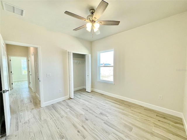 unfurnished bedroom featuring light wood-type flooring, visible vents, a ceiling fan, a closet, and baseboards