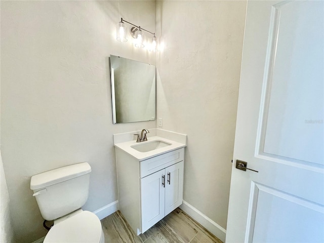 half bathroom featuring baseboards, toilet, wood finished floors, and vanity