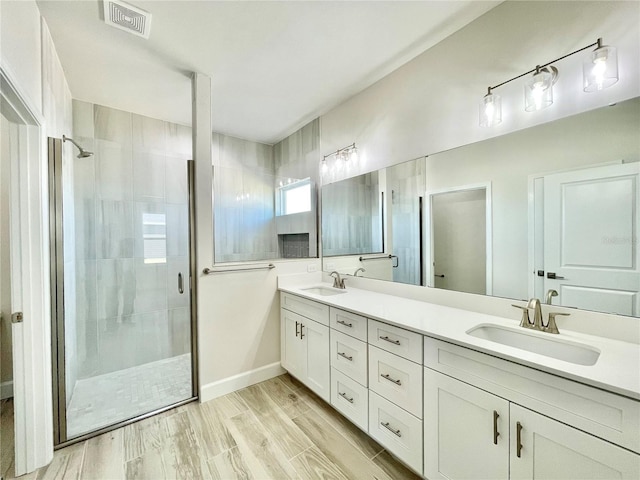 bathroom with a shower stall, wood finished floors, visible vents, and a sink