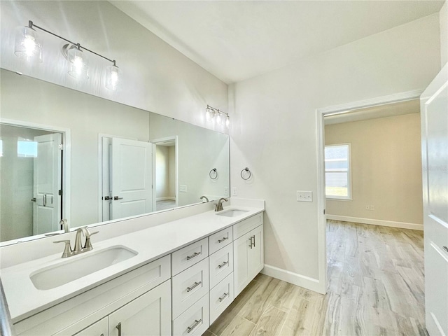 full bathroom featuring double vanity, wood finished floors, baseboards, and a sink