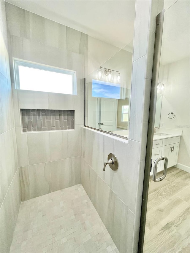 full bathroom featuring wood finished floors, vanity, and a tile shower