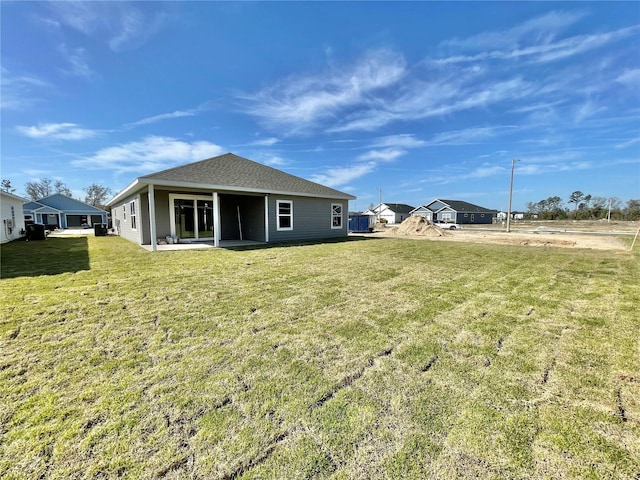 back of house with a lawn, roof with shingles, and a patio area