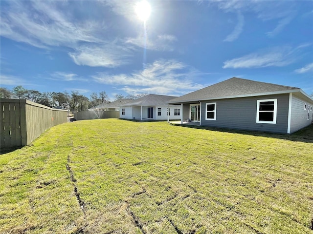 rear view of house with fence and a lawn