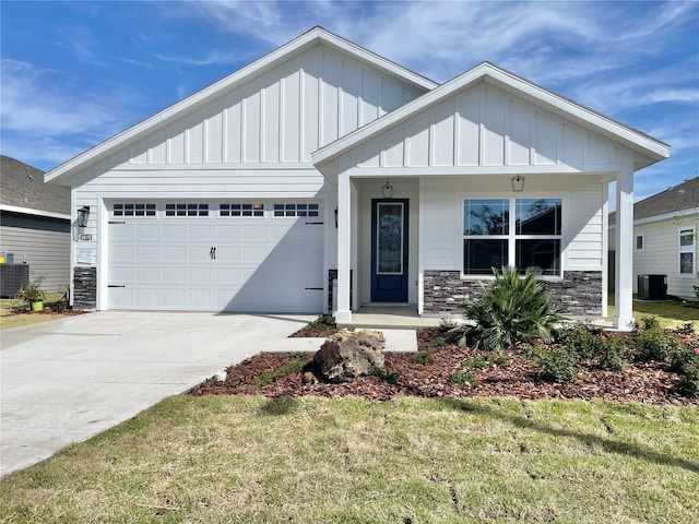 view of front of house featuring cooling unit, driveway, a garage, stone siding, and board and batten siding