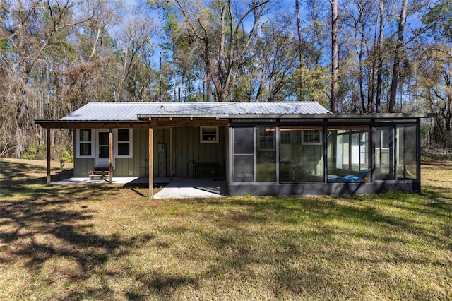 rear view of house featuring metal roof, a lawn, board and batten siding, and a sunroom