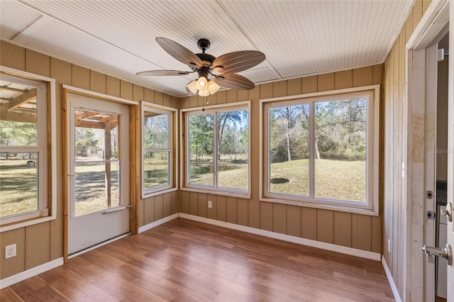 unfurnished sunroom featuring wood ceiling, a wealth of natural light, and ceiling fan