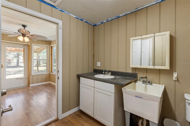 half bathroom featuring a ceiling fan, vanity, and wood finished floors