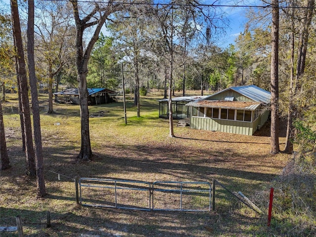 view of yard featuring a gate, an outbuilding, a carport, and fence