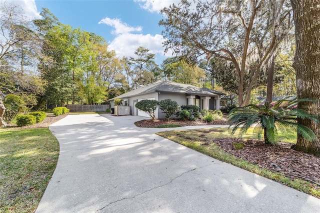 view of front facade featuring stucco siding, an attached garage, driveway, and fence