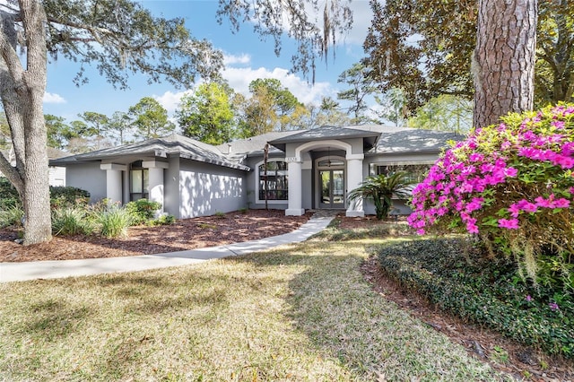 view of front of home featuring a front lawn, french doors, and stucco siding