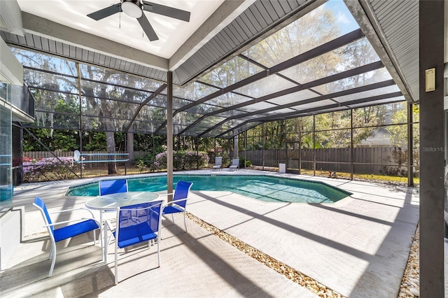 view of pool with glass enclosure, a patio, a fenced backyard, and ceiling fan