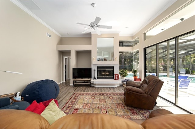 living area featuring a ceiling fan, wood finished floors, visible vents, and ornamental molding