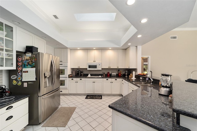 kitchen with visible vents, a sink, tasteful backsplash, white appliances, and a raised ceiling